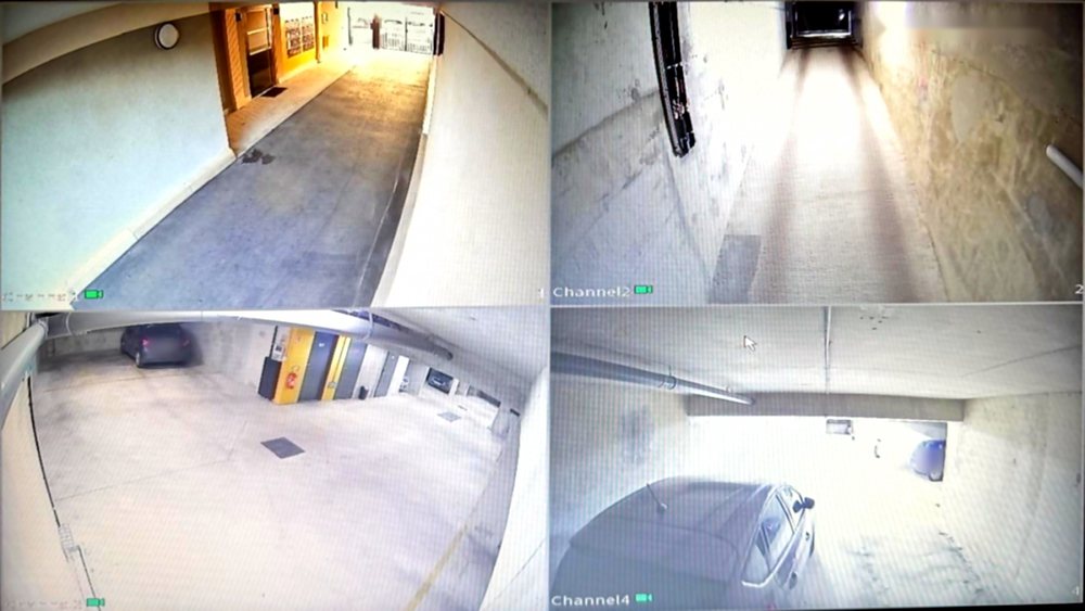 Écran de contrôle affichant quatre caméras : entrée, rampe et deux vues du parking