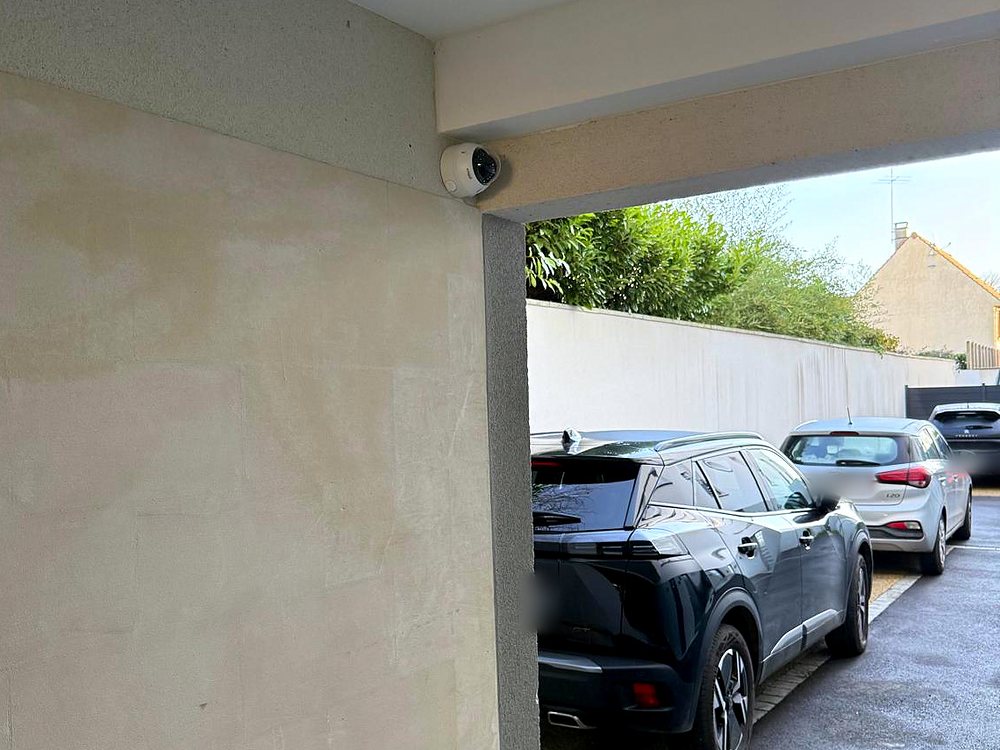 Caméra dôme sous un porche, orientée vers une allée extérieure
