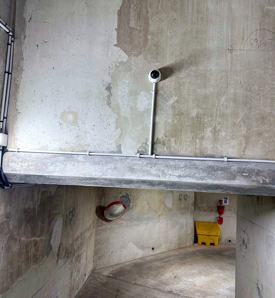 Caméra dôme fixée sur le mur d’une rampe de parking, câble sous tube
